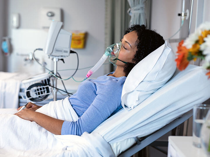 African American female patient sleeping in a hospital room wearing a ventilator mask for oxygen