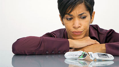 Woman looking at broken cell phone 